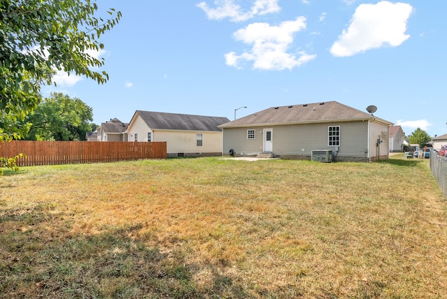 rear view of house with cooling unit and a lawn