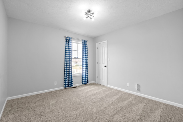 carpeted empty room featuring a textured ceiling