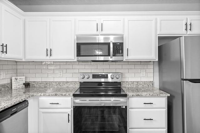 kitchen with white cabinetry, backsplash, stainless steel appliances, and light stone countertops