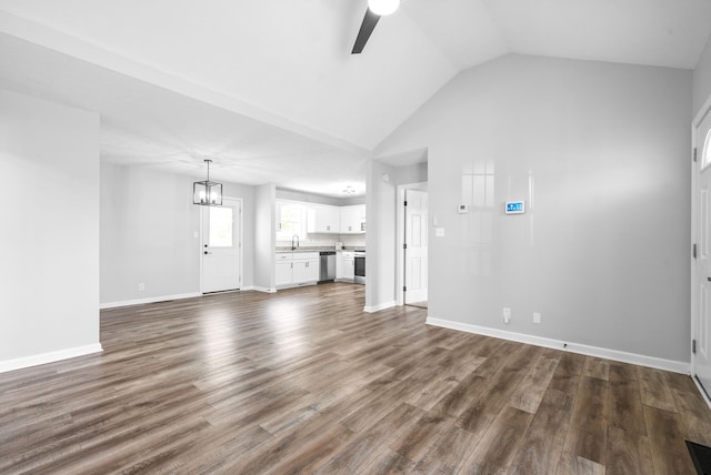 unfurnished living room featuring ceiling fan with notable chandelier, wood-type flooring, sink, and vaulted ceiling