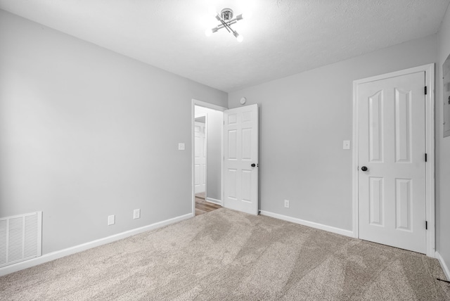 carpeted empty room featuring a textured ceiling