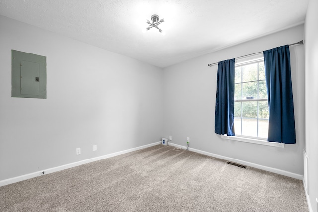 empty room with electric panel, carpet flooring, and a textured ceiling