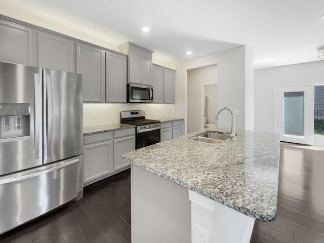 kitchen with light stone countertops, stainless steel appliances, sink, dark hardwood / wood-style floors, and decorative backsplash