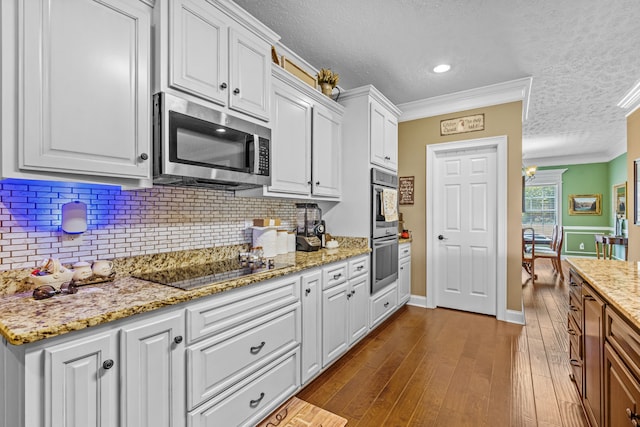 kitchen with white cabinets, backsplash, hardwood / wood-style flooring, crown molding, and stainless steel appliances