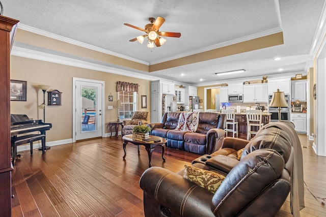 living room with a textured ceiling, crown molding, ceiling fan, and dark hardwood / wood-style floors