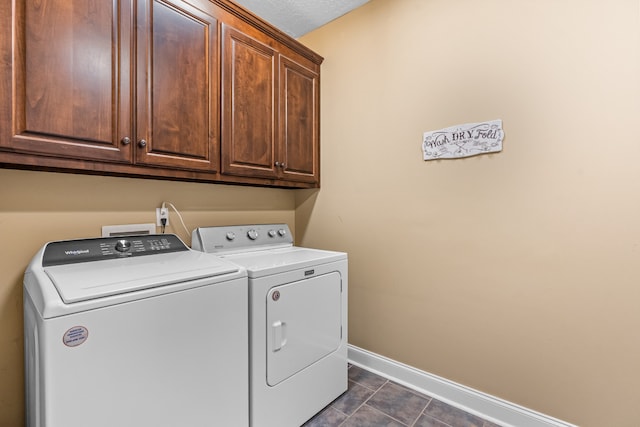 clothes washing area with a textured ceiling, cabinets, independent washer and dryer, and dark tile patterned flooring