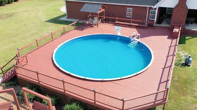 view of pool with a wooden deck and a lawn