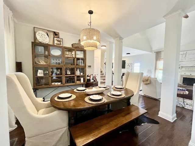 dining space featuring an inviting chandelier, dark hardwood / wood-style floors, decorative columns, ornamental molding, and lofted ceiling