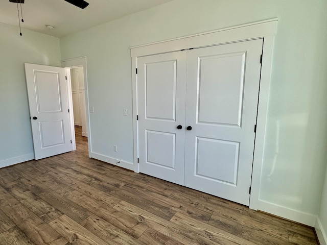 unfurnished bedroom featuring ceiling fan, wood-type flooring, and a closet