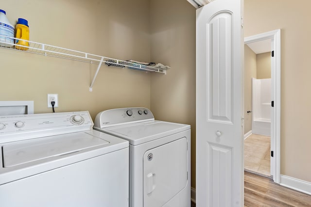 clothes washing area featuring washing machine and clothes dryer and light hardwood / wood-style flooring