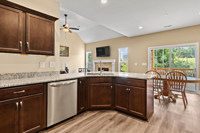 kitchen with ceiling fan, sink, stainless steel dishwasher, light hardwood / wood-style flooring, and a tiled fireplace