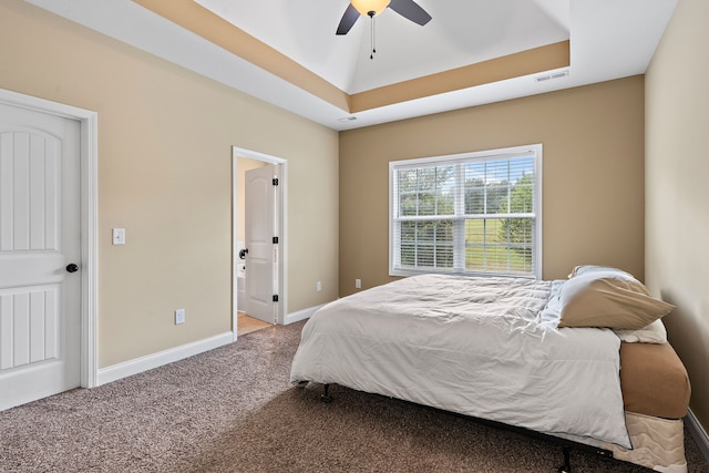 carpeted bedroom featuring ceiling fan and a raised ceiling