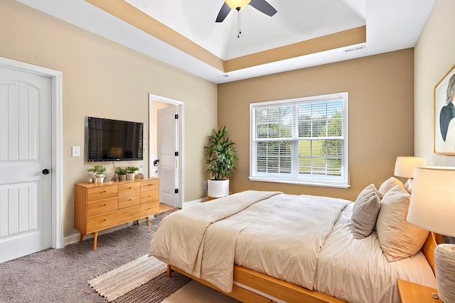 carpeted bedroom featuring a tray ceiling and ceiling fan