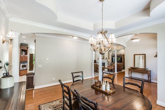 dining room featuring crown molding, a raised ceiling, an inviting chandelier, and wood-type flooring