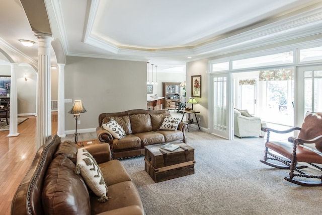 living room with ornamental molding, a raised ceiling, light hardwood / wood-style flooring, and decorative columns