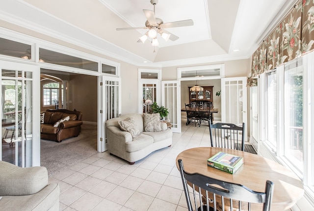 tiled living room with a tray ceiling, ceiling fan, and ornamental molding