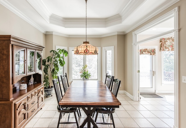 tiled dining space with ornamental molding and a tray ceiling