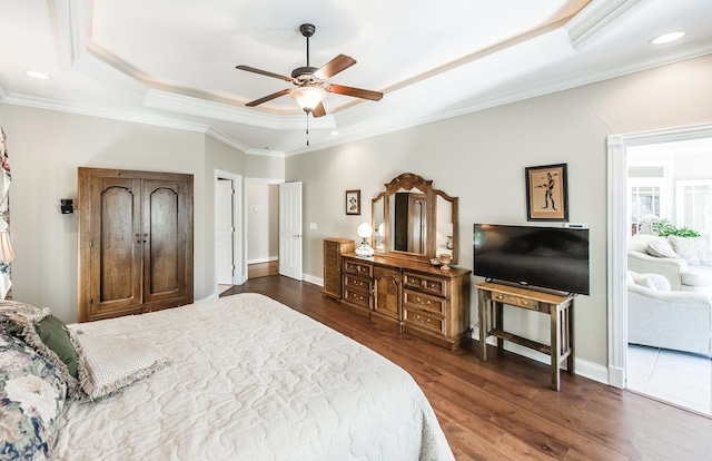 bedroom featuring crown molding, dark wood-type flooring, ceiling fan, and a tray ceiling