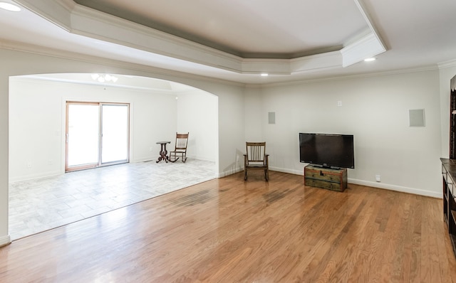 living room featuring a tray ceiling, wood-type flooring, and ornamental molding