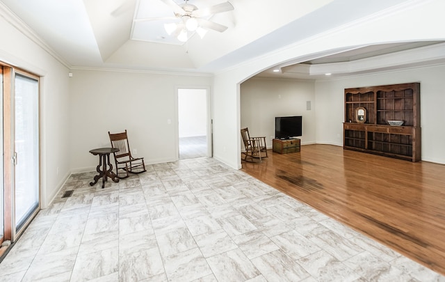 living room featuring light hardwood / wood-style flooring, ceiling fan, ornamental molding, and a tray ceiling