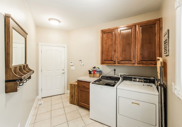 laundry area featuring washing machine and clothes dryer, cabinets, and light tile patterned flooring