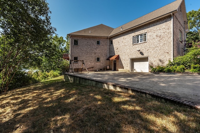 back of house featuring a garage and a lawn