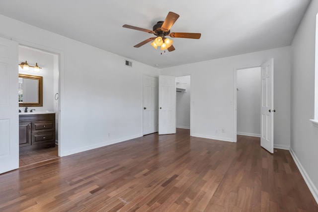 unfurnished bedroom featuring dark wood-type flooring, ceiling fan, ensuite bathroom, and sink