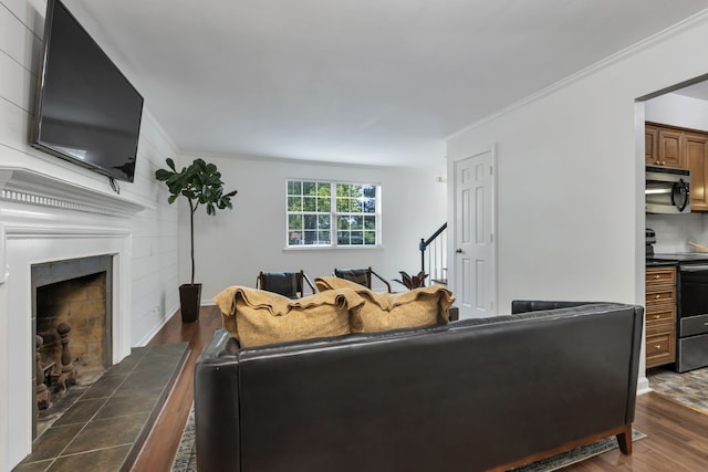 living room with ornamental molding, dark wood-type flooring, and a tiled fireplace