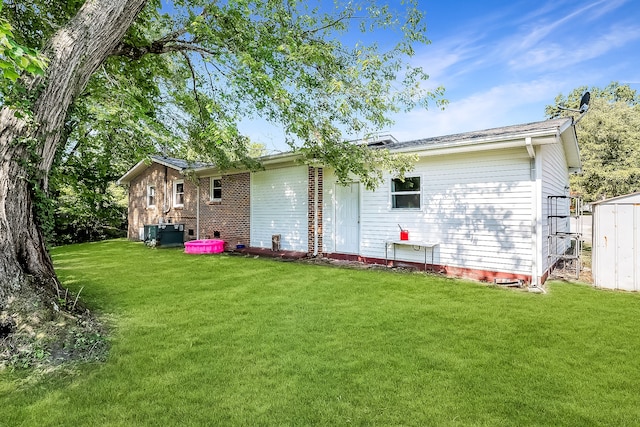 rear view of property with a lawn and central air condition unit