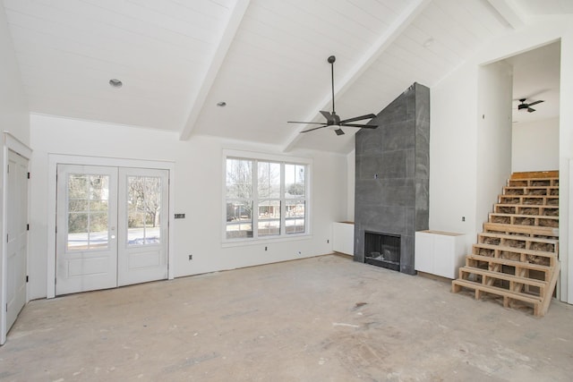 unfurnished living room with ceiling fan, a large fireplace, lofted ceiling with beams, and french doors