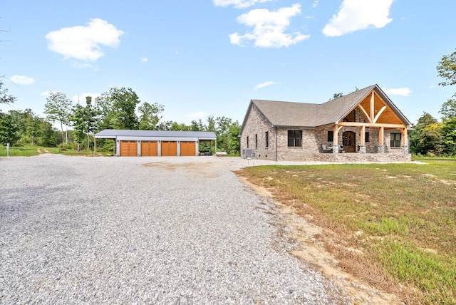 view of front facade featuring a garage, a front lawn, an outdoor structure, and gravel driveway