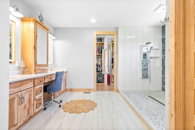 full bath featuring baseboards, wood finished floors, a walk in closet, walk in shower, and vanity