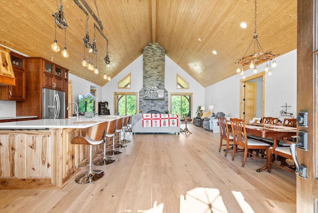 kitchen featuring a breakfast bar, wood ceiling, light countertops, hanging light fixtures, and stainless steel fridge with ice dispenser