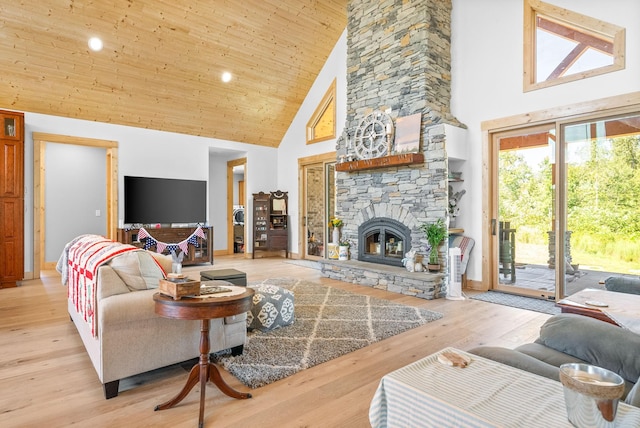 living room with light wood-style floors, wooden ceiling, high vaulted ceiling, and a stone fireplace