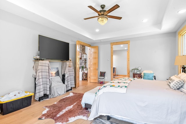 bedroom with recessed lighting, a raised ceiling, ceiling fan, and light wood finished floors