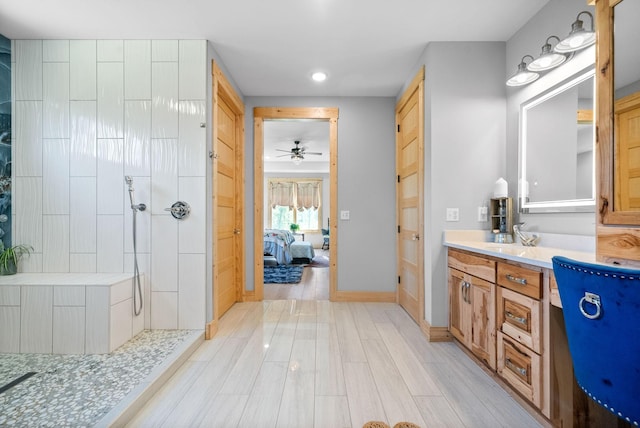 ensuite bathroom with baseboards, connected bathroom, wood finished floors, vanity, and a walk in shower