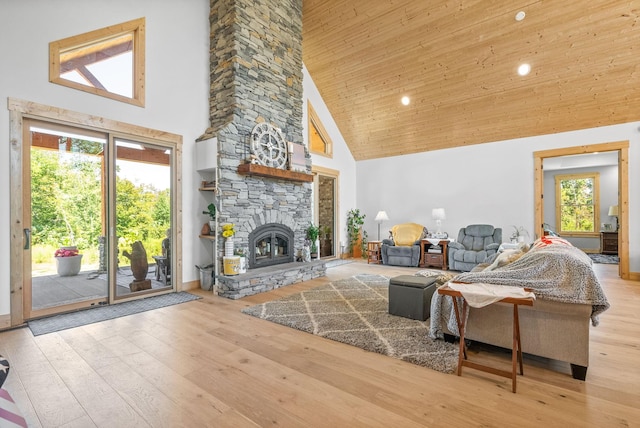 living area featuring high vaulted ceiling, light wood-type flooring, wood ceiling, and a fireplace