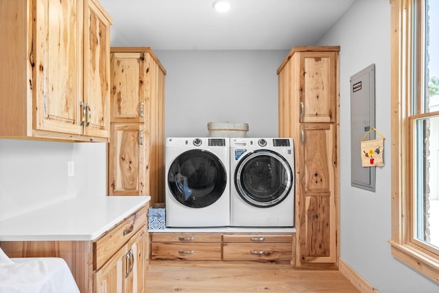 laundry area featuring light wood-type flooring, washing machine and dryer, cabinet space, and plenty of natural light