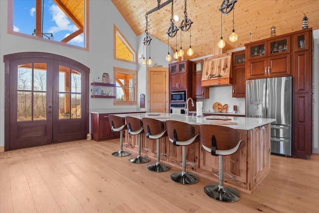 kitchen with a center island with sink, wooden ceiling, hanging light fixtures, stainless steel appliances, and french doors