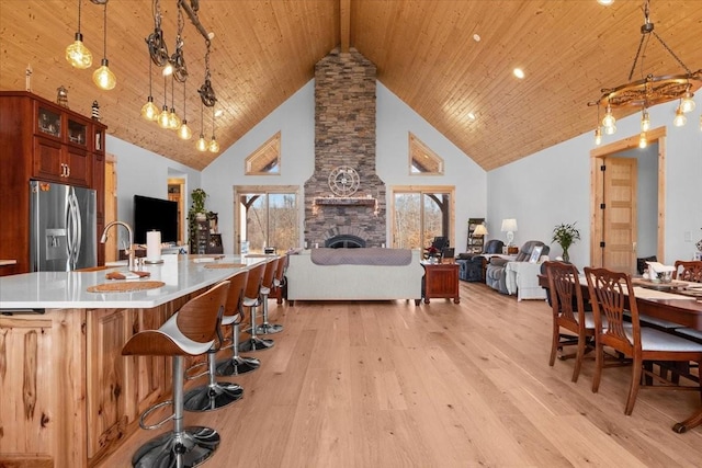 kitchen with stainless steel fridge with ice dispenser, wood ceiling, open floor plan, light countertops, and pendant lighting