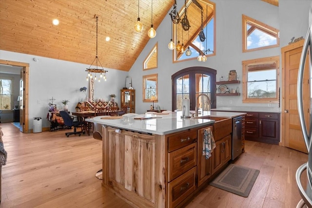 kitchen with arched walkways, decorative light fixtures, light countertops, french doors, and a center island with sink