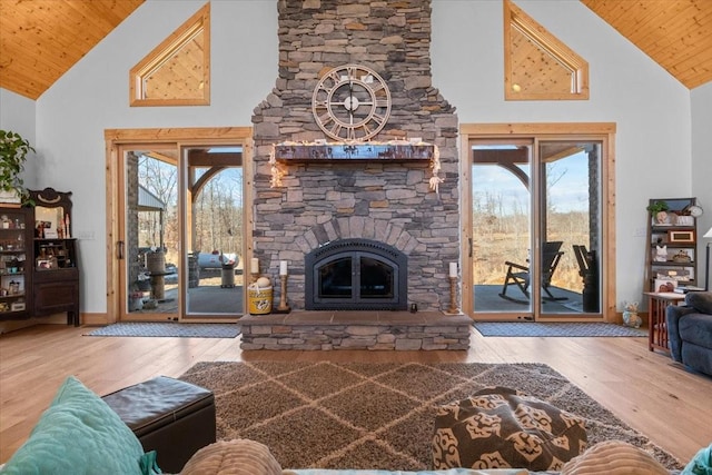 living area featuring high vaulted ceiling, wood ceiling, a stone fireplace, and wood finished floors