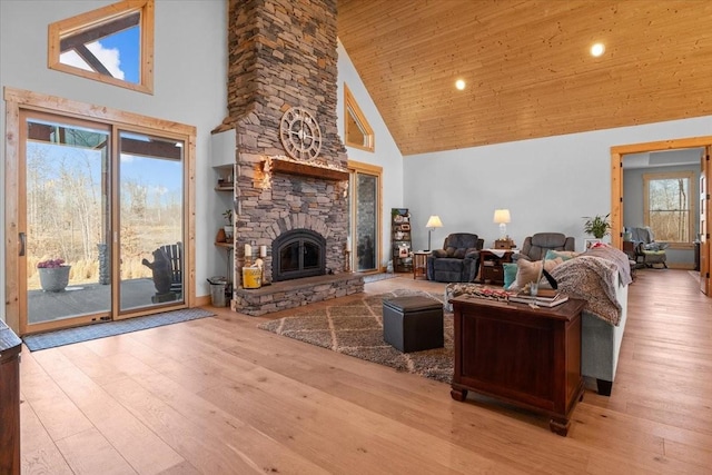 living room with light wood-style floors, wood ceiling, high vaulted ceiling, and a stone fireplace