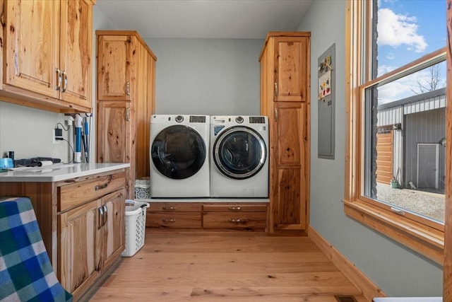 laundry area with light wood-style flooring, a wealth of natural light, washer and clothes dryer, and baseboards