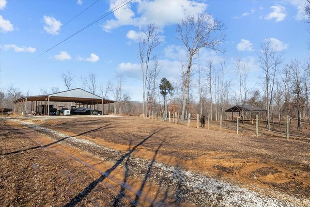 view of yard featuring dirt driveway, a carport, and a rural view