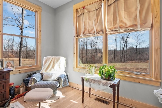 sitting room with baseboards, visible vents, and wood finished floors