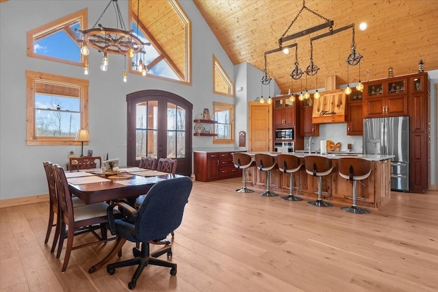 dining space with arched walkways, high vaulted ceiling, light wood-style flooring, wood ceiling, and french doors