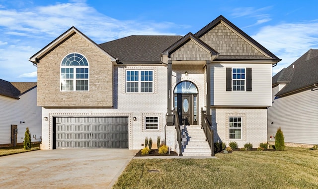 raised ranch featuring a garage, concrete driveway, brick siding, and a front lawn