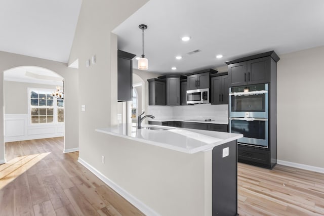 kitchen featuring stainless steel appliances, light wood-type flooring, light countertops, and a sink