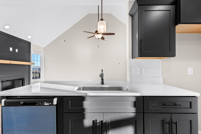 kitchen featuring a large fireplace, dishwasher, vaulted ceiling, light countertops, and a sink